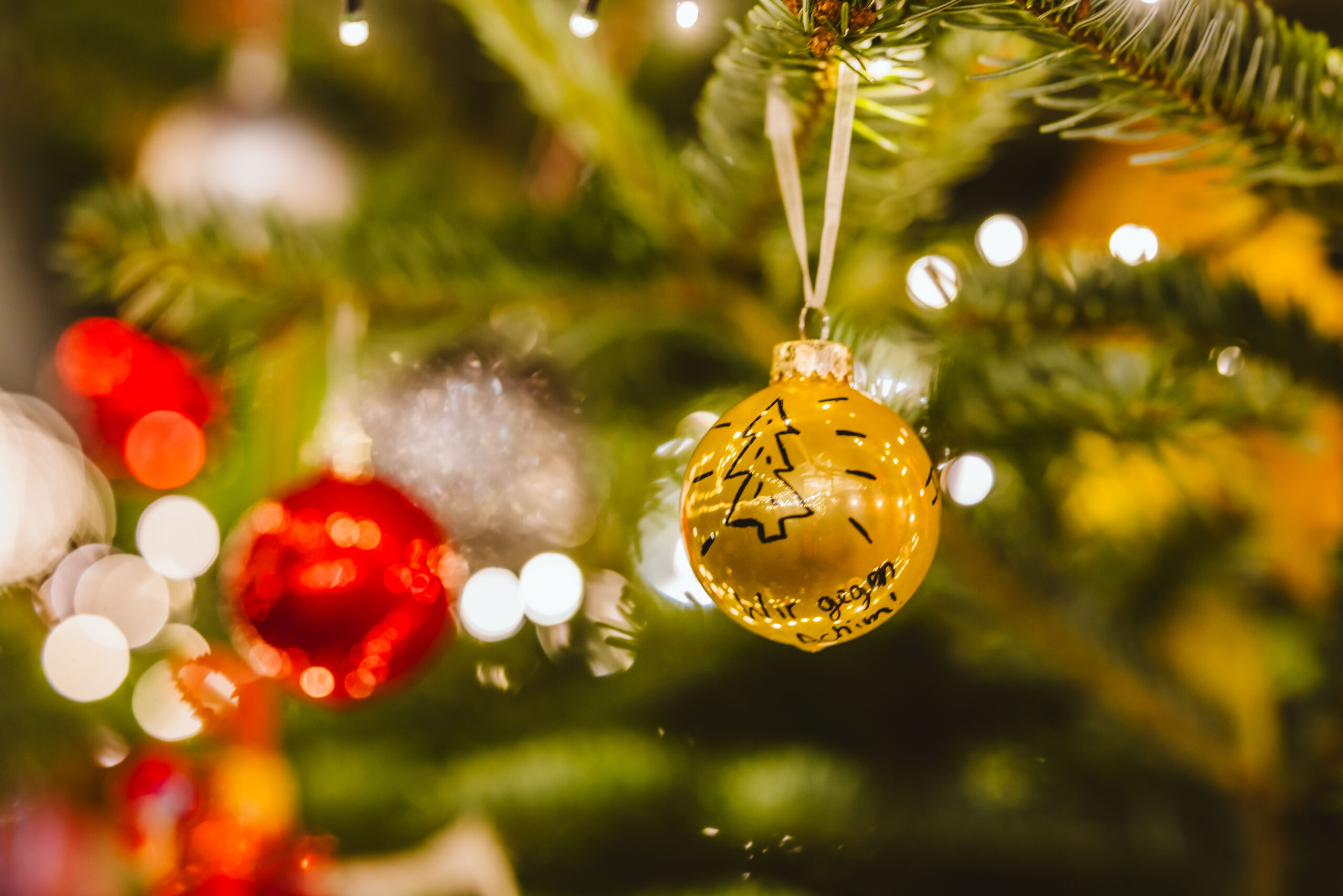 Weihnachtskugel am geschmückten Baum mit warmen Lichtern