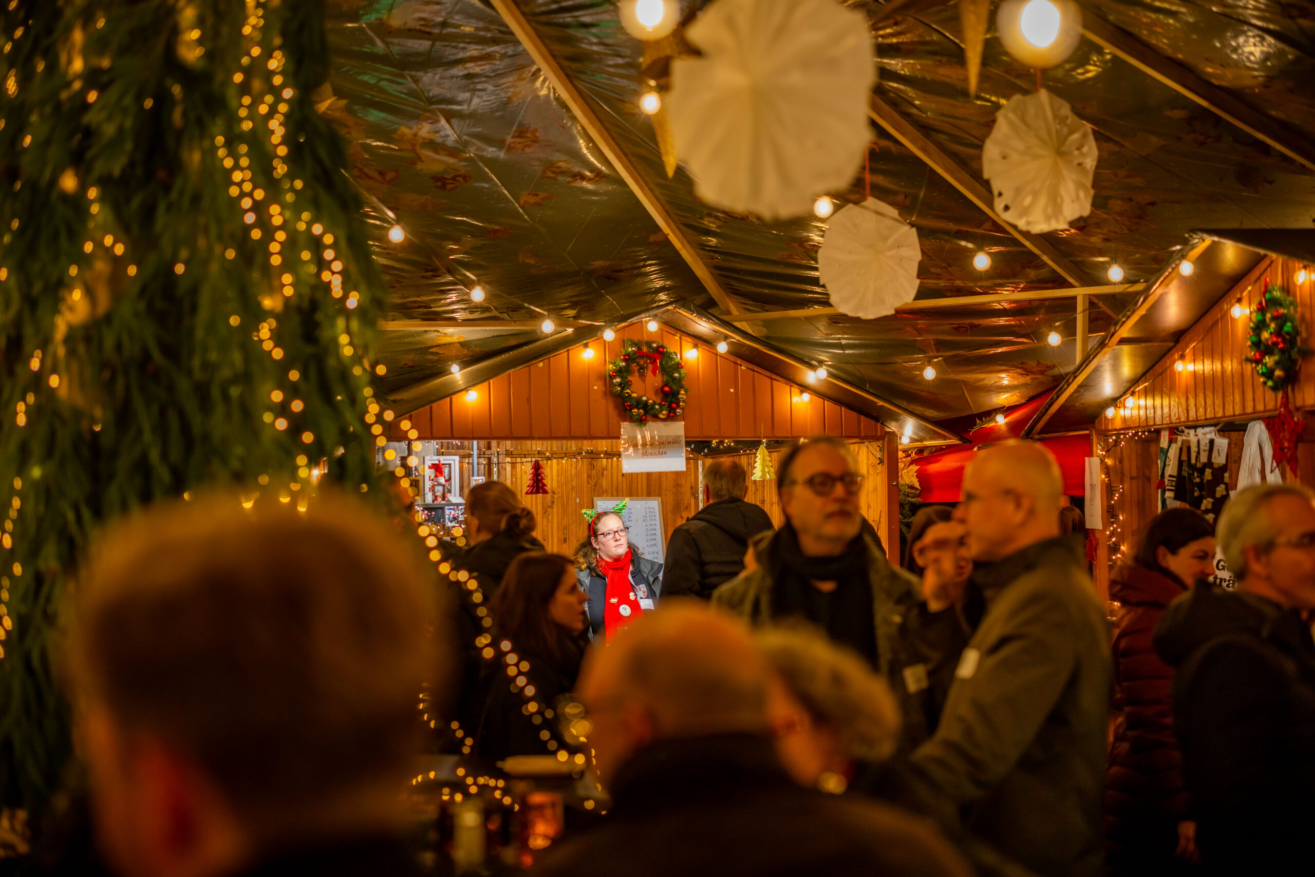 Gäste zwischen weihnachtlicher Dekoration und warm beleuchteten Hütten